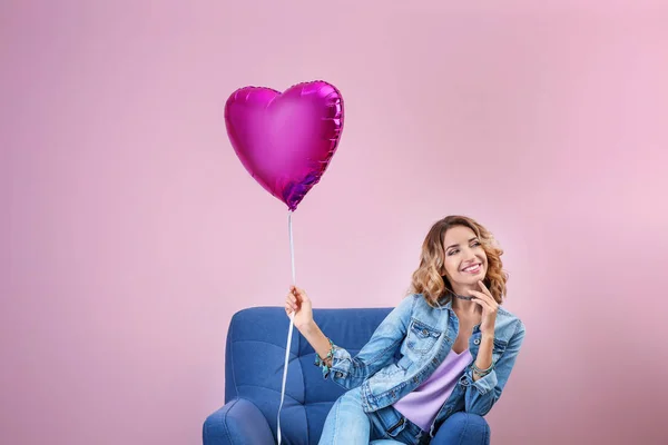 Atrakcyjna, młoda kobieta z balonem, siedząc w fotelu na kolor tła — Zdjęcie stockowe