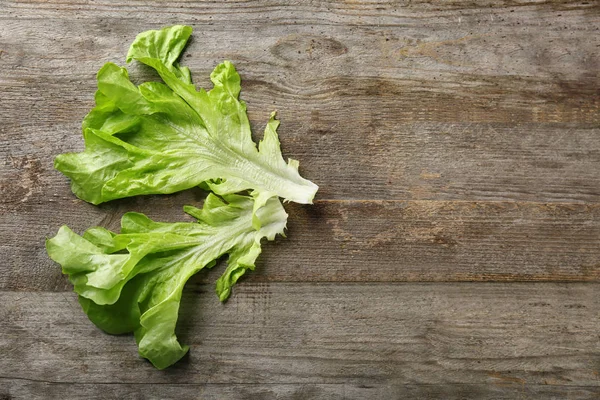 Feuilles de salade verte fraîche sur table en bois — Photo