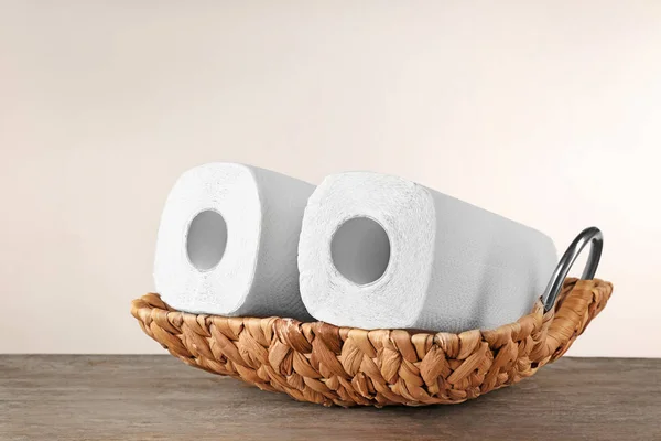 Wiklinowy kosz z rolki ręczników papierowych na stole przed jasnym tle — Zdjęcie stockowe