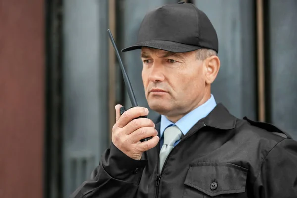 Male security guard using portable radio outdoors — Stock Photo, Image