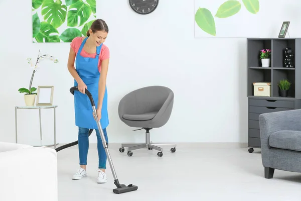 Young woman hoovering floor at home — Stock Photo, Image