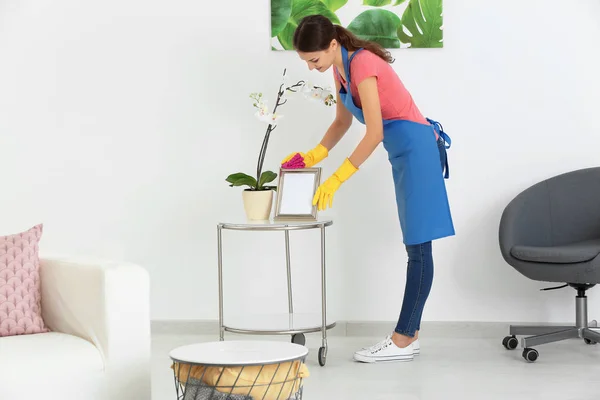 Mujer joven limpiando polvo mientras limpia plana — Foto de Stock