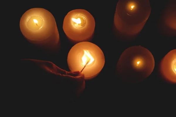 Woman lightening candles on dark background — Stock Photo, Image