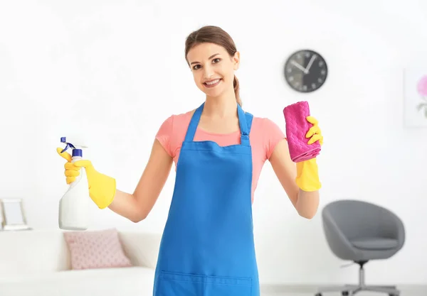 Wanita muda dengan botol deterjen dan kain di flat — Stok Foto