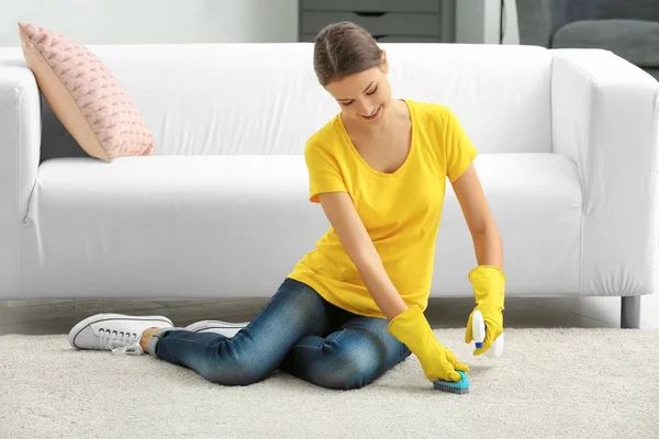 Giovane donna pulizia tappeto a casa — Foto Stock
