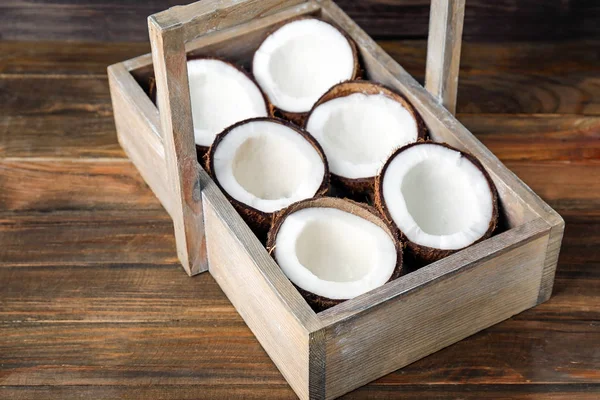 Caixa com metades de coco sobre fundo de madeira — Fotografia de Stock