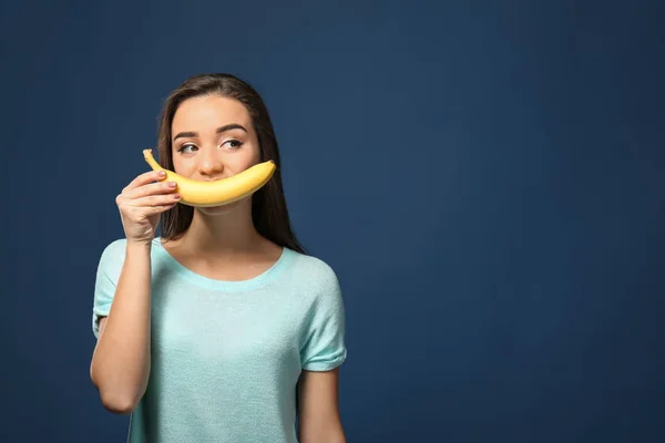 Привлекательная молодая женщина позирует с бананом на цветном фоне — стоковое фото