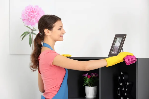 Mujer joven limpiando polvo mientras limpia plana — Foto de Stock