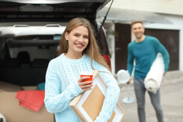 Pareja joven descargando mercancías de su coche en el día en movimiento — Foto de Stock