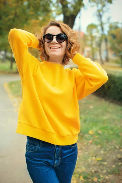 Mooie lachende vrouw in heldere gele trui buitenshuis — Stockfoto