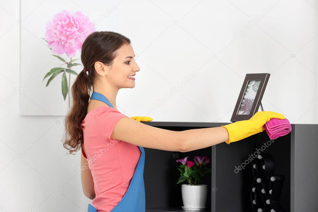 Young woman wiping dust while cleaning flat