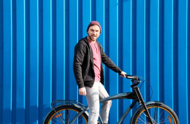 Yakışıklı genç hipster adam yakınındaki duvara açık havada bisiklet ile