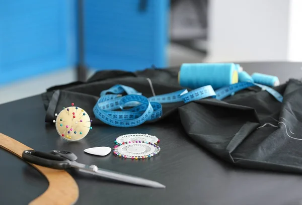 Black fabric and sewing accessories on table — Stock Photo, Image