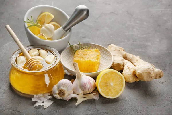 Sammansättning med honung och vitlök som kall naturläkemedel på grå texturerat bakgrund — Stockfoto