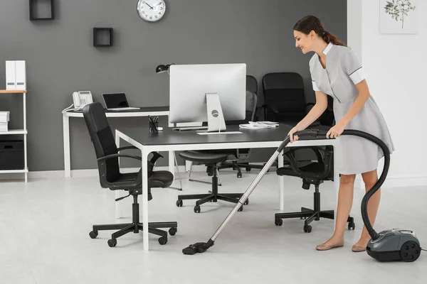 Giovane donna aspirapolvere pavimento in ufficio utilizzando aspirapolvere — Foto Stock