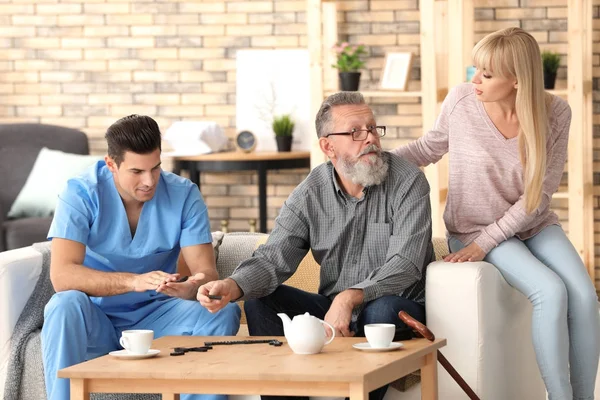 Cuidador con el hombre mayor y su hija en casa — Foto de Stock