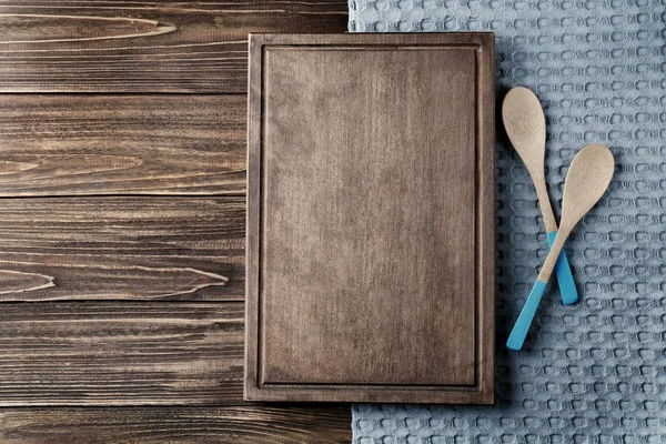 Toalla de cocina limpia, tabla y cucharas en la mesa de madera, vista superior — Foto de Stock