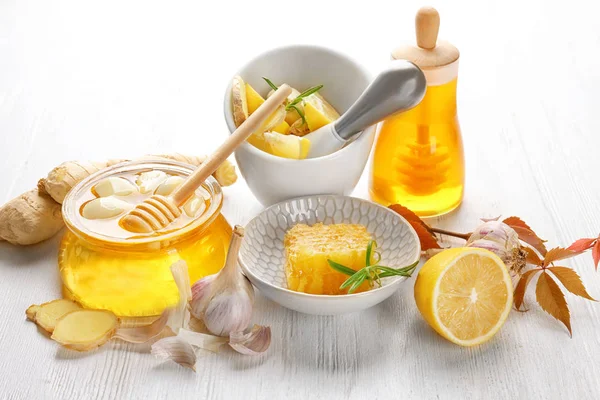 Composition avec du miel et de l'ail comme remèdes naturels contre le froid sur fond de bois blanc — Photo