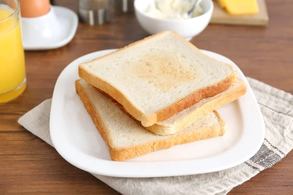 Plaat met smakelijke krokante toast op houten tafel — Stockfoto