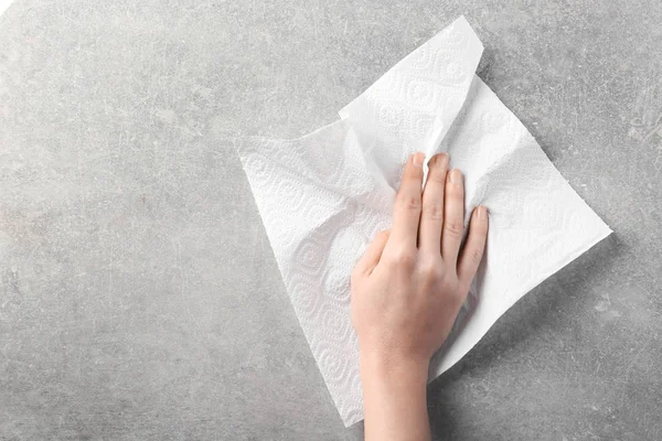 Hand of woman wiping light surface with paper towel