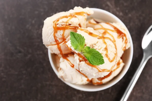 美味的冰淇淋与焦糖顶在碗上桌 — 图库照片