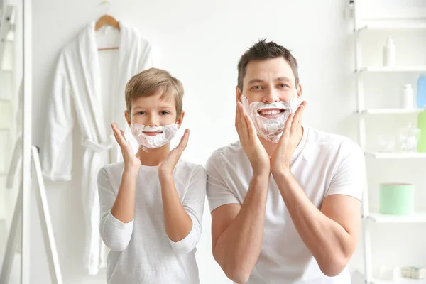 Father and son shaving together in bathroom