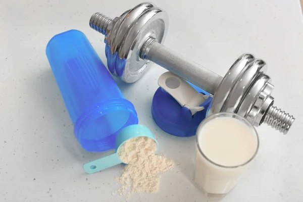 Scoop con proteine in polvere, manubrio e bicchiere di latte in tavola — Foto Stock
