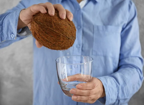 Mujer vertiendo agua de coco fresca de la nuez en el vidrio, primer plano — Foto de Stock