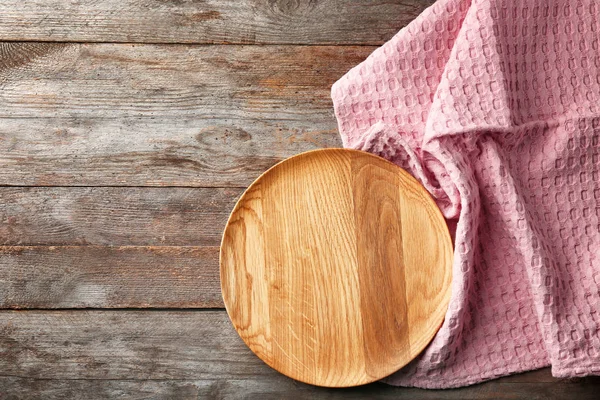 Toalha de cozinha limpa e placa na mesa de madeira, vista superior — Fotografia de Stock