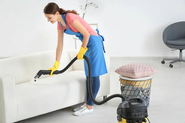 Женщина убирает грязь с дивана с помощью пылесоса — стоковое фото