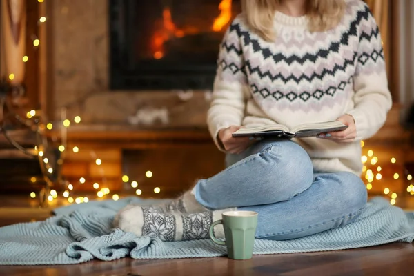 Młoda kobieta zrelaksować czytając książkę w salon urządzony na ferie zimowe — Zdjęcie stockowe
