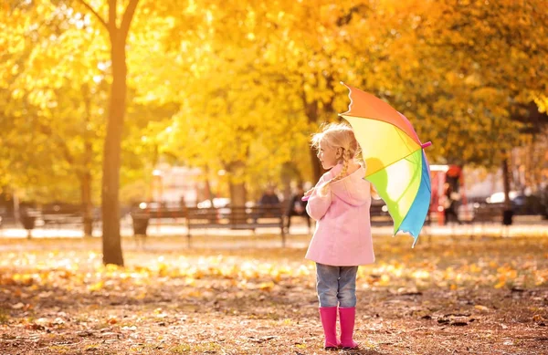 Dziewczynka z rainbow parasol w jesienny park — Zdjęcie stockowe