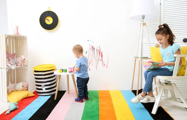 Niño pequeño dibujo y niña leyendo en casa — Foto de Stock