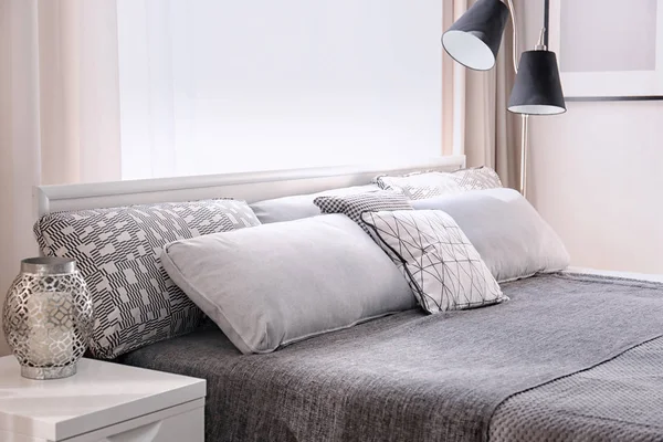 Pohodlná postel s polštáři v místnosti se světlem — Stock fotografie