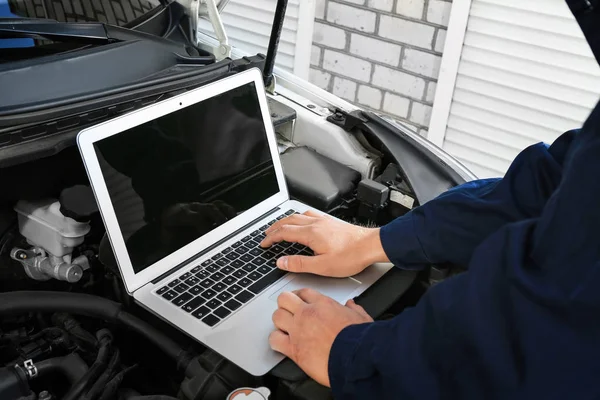 Mecánico automático usando el programa de diagnóstico de la computadora mientras que repara el coche al aire libre — Foto de Stock