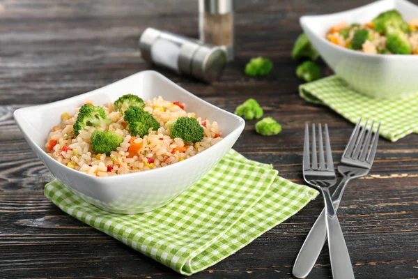 Delicioso pilaf de arroz com brócolis em tigela na mesa de madeira — Fotografia de Stock
