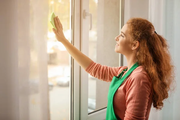 Mooie vrouw schoonmaken raam thuis — Stockfoto