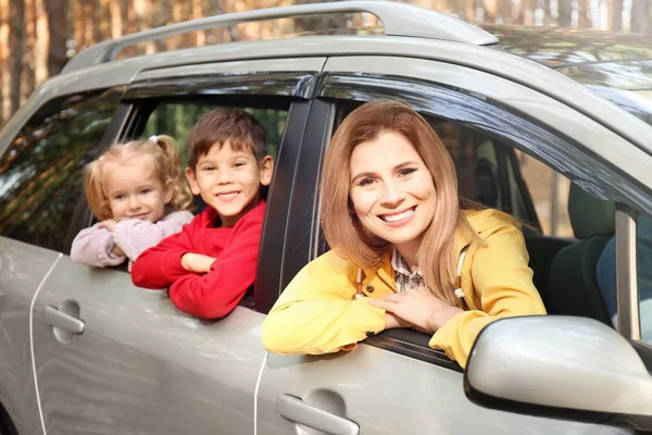 Lycklig kvinna med hennes små barn i bil på solig dag — Stockfoto