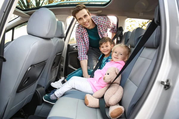 Чоловік кріпив ремені безпеки на своїх маленьких дітей в машині — стокове фото