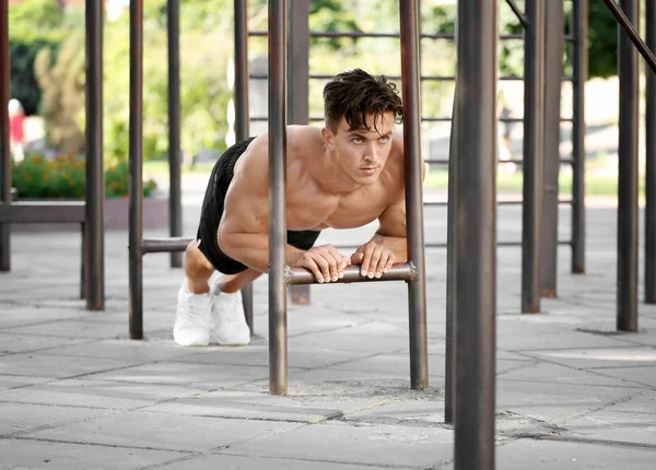 Bonito jovem musculoso exercitando ao ar livre — Fotografia de Stock