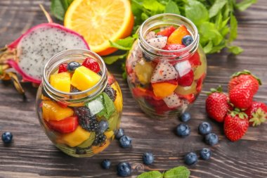 Kavanoz ahşap masa üzerinde lezzetli meyve salatası ile