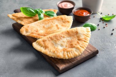 Gri arka plan üzerinde derin kızarmış samosas ile ahşap tahta