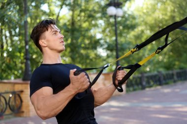 Trx kayışları ile açık havada egzersiz kas yakışıklı genç