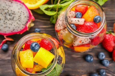 Kavanoz ahşap masa üzerinde lezzetli meyve salatası ile