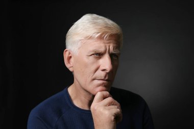 Koyu arka plan üzerinde düşünceli olgun adam portresi