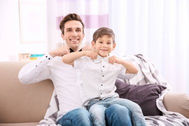 Baba ve oğul evde koltukta oturan bowties gömlek