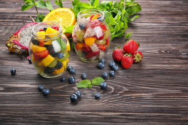 Kavanoz ahşap masa üzerinde lezzetli meyve salatası ile