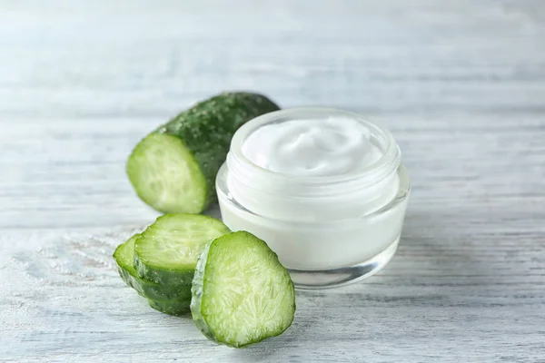 Jar with body cream and cucumber slices on wooden background — Stock Photo, Image