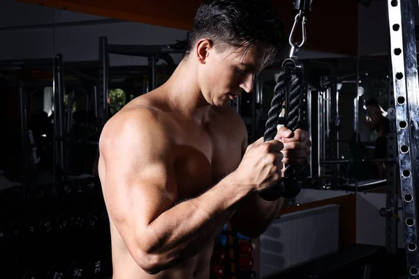 Hombre joven entrenando en una máquina de ejercicios en gimnasio —  Fotos de Stock