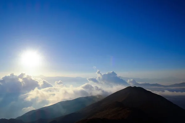 Sol brillando en el cielo nublado sobre las montañas —  Fotos de Stock